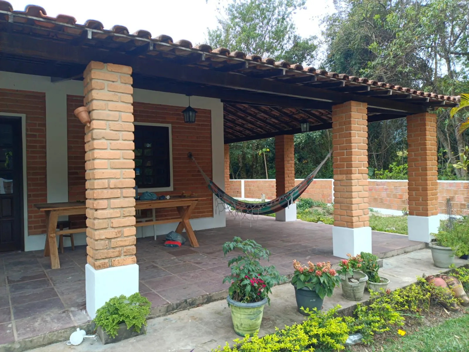 Varanda em tijolos e madeira voltada para o jardim